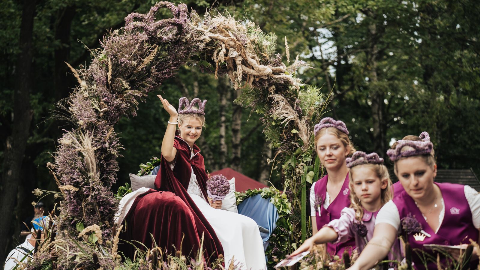 Jubelnde Heideköniginnen mit Blütenbogen in der Heide
